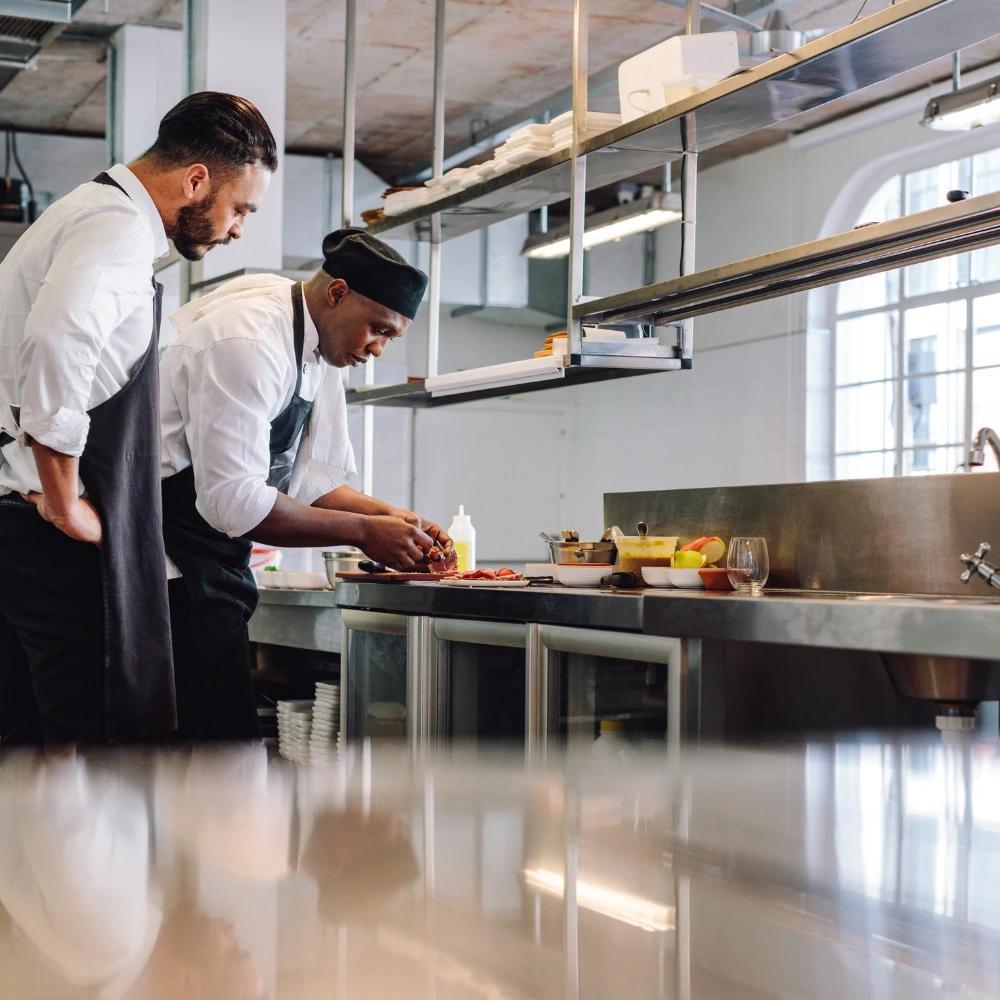 Two chefs preparing food on a prep table
